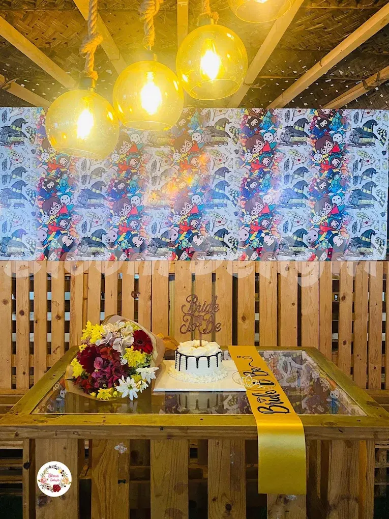 A birthday cake and flower bouquet on a table against a wizard-patterned wall