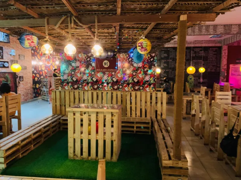 Wooden pallet booths under a timber pergola with hanging lamps