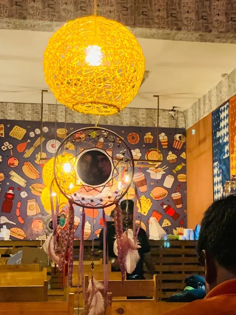 A colourful illustrated food mural with a dreamcatcher mirror and woven lamp
