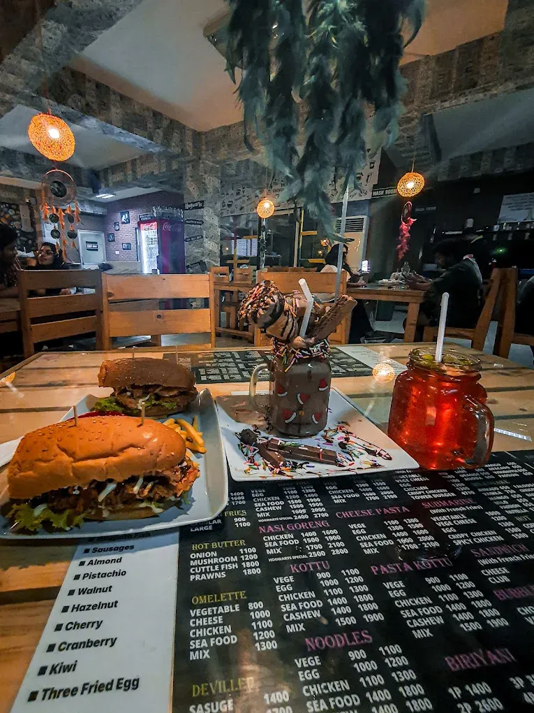 Burgers with chips, a chocolate milkshake and an iced drink on a café table